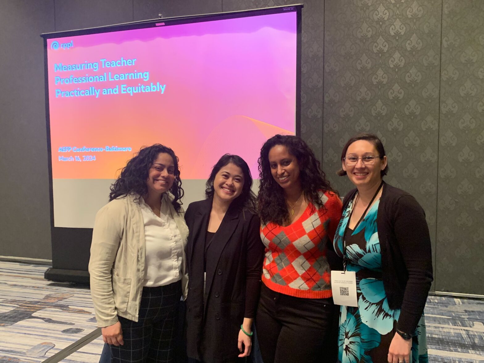 four women smiling in front of a presentation screen that reads "measuring teacher professional learning practically and ethically"