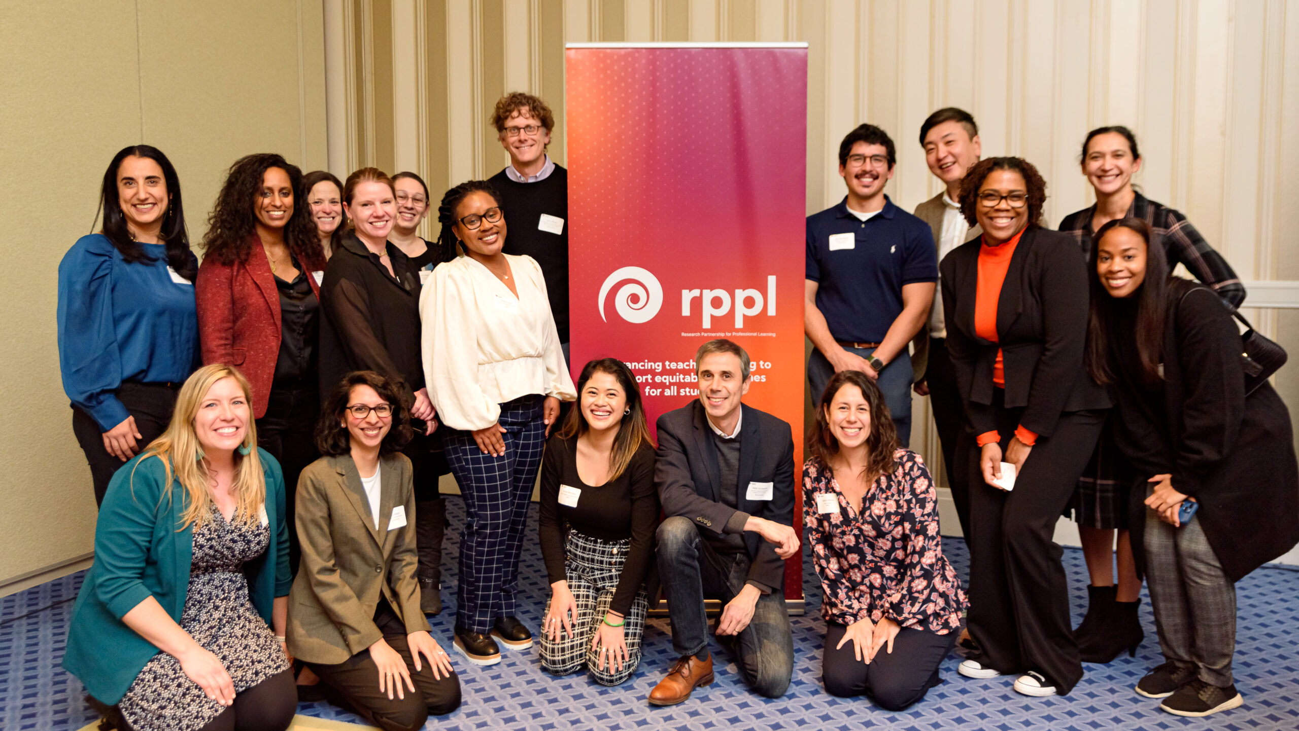 Group of 17 people standing and squatting around a RPPL banner