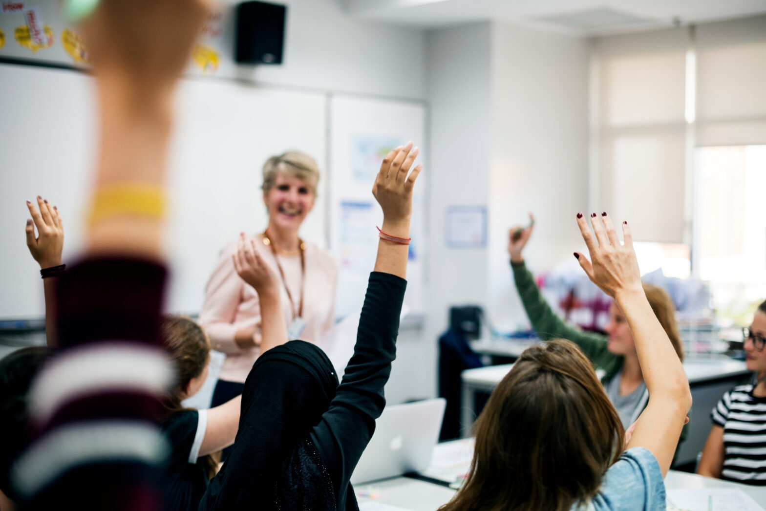 Teacher looking students raising their hands